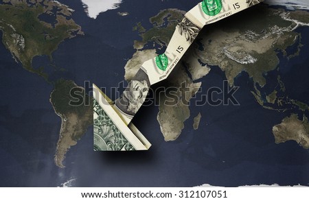 Origami dollar arrow pointing down over a world map