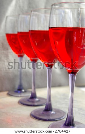 Four glasses of red wine in a line (left side of front glass is sharp)