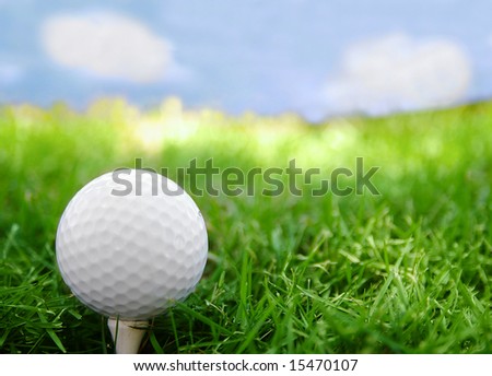 Golf ball closeup, on the tee, with grass and sky