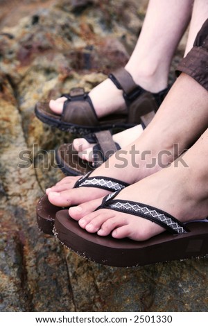 A close up of a two pairs of feet wearing sandals - a girl and guy