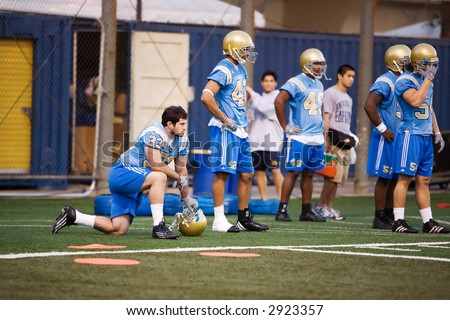 UCLA Bruins football players waiting at the sidelines during practice