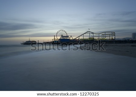 Horizontal image of the Pacific Wheel at the Santa Monica Pier amusement park.   Long exposure with misty looking waves during sunset