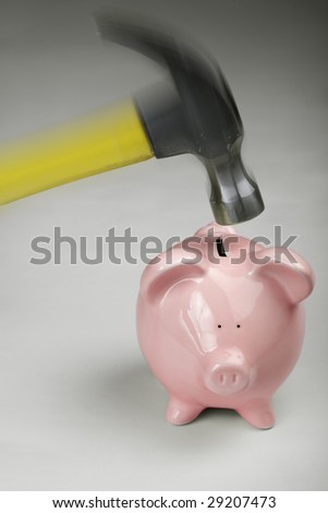 Vertical image of a pink piggy bank about to be smashed open with a hammer.