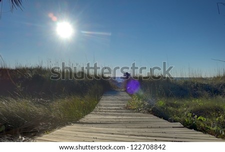The sun on a wooden walkway to the Atlantic Ocean near a luxury beach house in Hilton Head, SC.