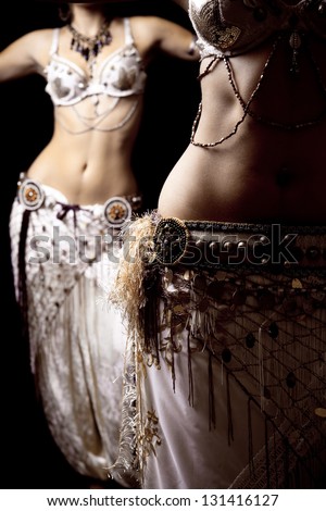 Close up of two belly dancers with white clothes.