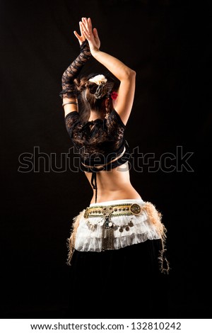 Belly Dancer on her back, dancing with arms up. Black background.