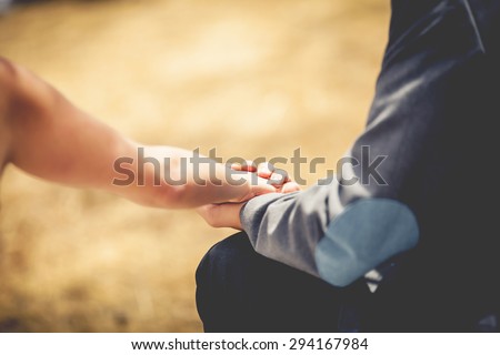 Close up of young loving couple holding hands. Vintage filter and zoom effect.