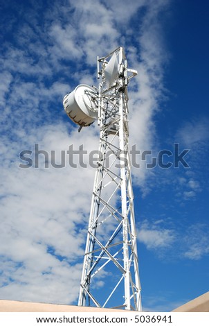 Cellular communication tower against a cloudy blue sky