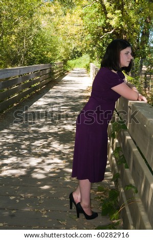 Petite young brunette on a wooden footbridge