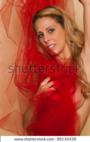 Pretty blonde woman nude wrapped in red tulle