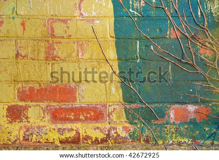 A brick wall, painted with peeling yellow and green paint.