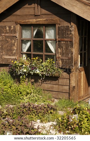 small wooden building with a window and window box set in a garden