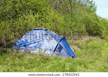 Blue tourist tent stands on the edge of the spring forest