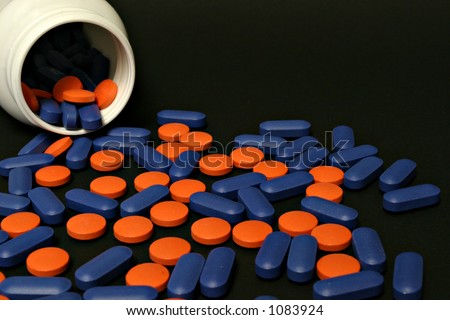blue and red pills isolated on black background with white bottle