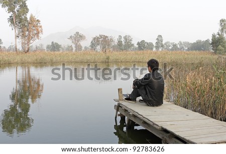man sitting on a wooden pier