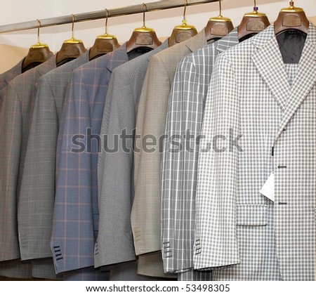 A row of designer suits hanging in a menswear store.