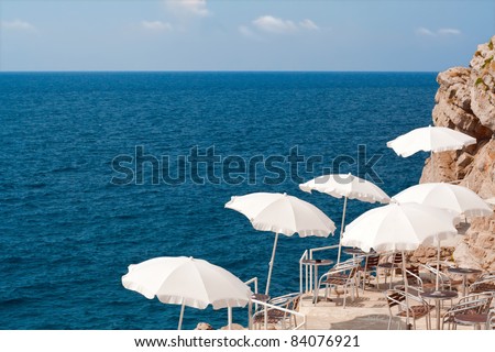 Croatia. Seaside restaurant in Dubrovnik with white umbrellas and clear sky. Adriatic sea.