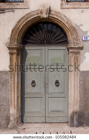 An Old Italian door made of wood weathered by the seasons gone by. Old Italian door.