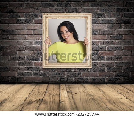 Abstract image of a beautiful woman trapped in a picture frame over a brick wall background.