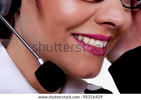 A close-up image of a beautiful woman with a friendly smile talking on a phone at a call center. Friendly service.