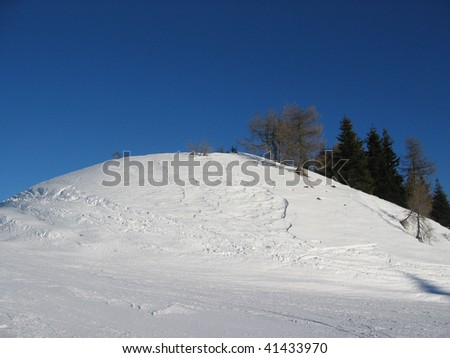 Calm snow-covered hill with empty blue sky