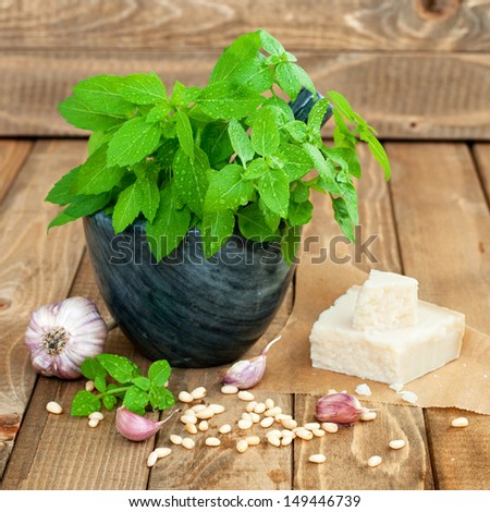 Fresh basil and another ingredients for pesto sauce on wooden table, square image