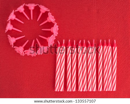 Pink birthday cake holders and candles on red serviette, napkin