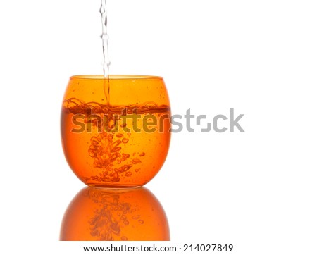 Cool clear water pouring into orange colour glass. Bubbles. Healthy hydration.
