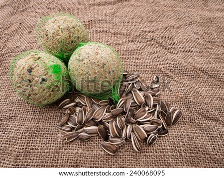 Feed the birds in winter - fat balls and sunflower seeds on hessian rustic background.