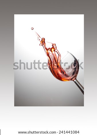 Rose wine splash caught midair. round bubble at point. White grey background.
