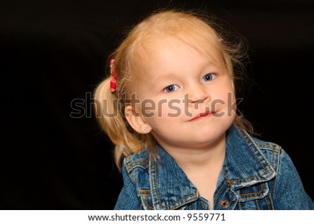 Young blond girl with a curious expression on her face. black background.