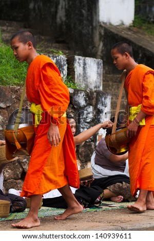 LUANG PRABANG, LAOS - SEPTEMBER15; Unidentified monks walk to collect alms and offerings on September 15, 2012 Laos. This procession is held every day in Luang prabang in the early morning