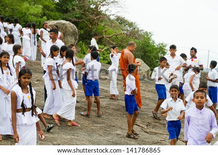 DAMBULLA, SRI LANKA - MARCH 25: School children and a buddhist monk on a school trip to Dambulla Caves on March 25, 2013 in Dambulla, Sri Lanka. Children are wearing typical white school uniforms.