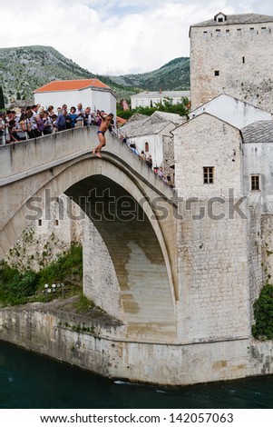 MOSTAR, BOSNIA- MAY 13: Man jumping from old bridge on MAY 13, 2013 in Mostar, Bosnia. It is a tradition for men to dive off the 21m bridge to impress visitors and earn some extra money.