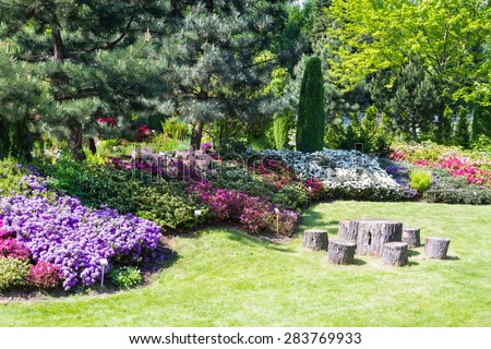BIELSKO BIALA, POLAND - MAY 16: well kept garden with azalea and rhododendrons and old wood as table and chairs in Bielsko Biala, Poland on May 16, 2015.