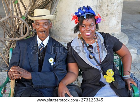 HAVANA, CUBA - FEBRUARY 11:  On February 11, 2012 an old man with a cigar and woman dressed in typical cuban garb pose for the entertainment of tourists in old Havana, Cuba.