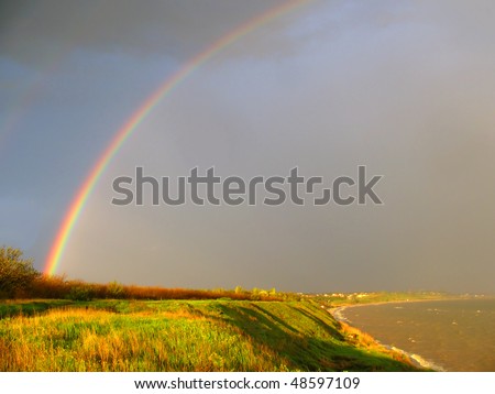 Landscape with a rainbow, green grass and the sea