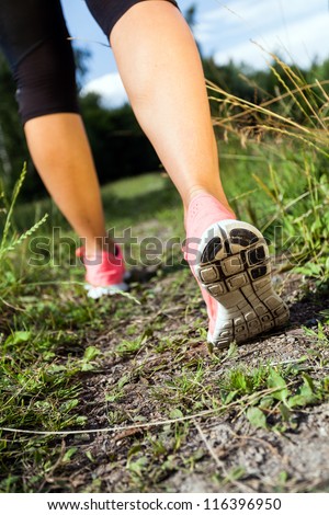 Walking or running legs in forest, adventure and exercising in summer nature. Jogging or training outside in summer nature, motivational health and fitness concept.