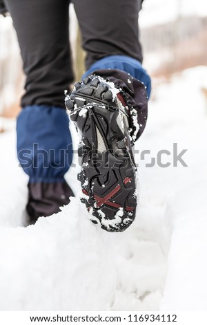 Walking legs and shoes on snow trail in winter forest. Recreation and healthy lifestyle outdoors in nature. Trekking shoes tracks