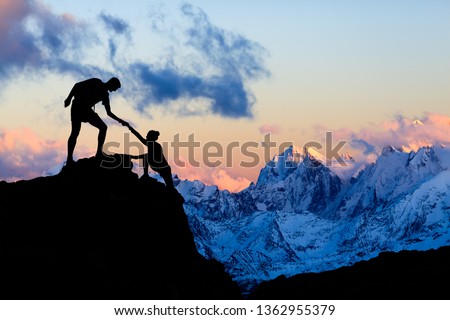 Teamwork couple helping hand, trust in mountains. Team of climbers man and woman hiking, help each other on top of mountain, climbing together, inspiring sunset on Elbrus, Russia. Photo stock © 