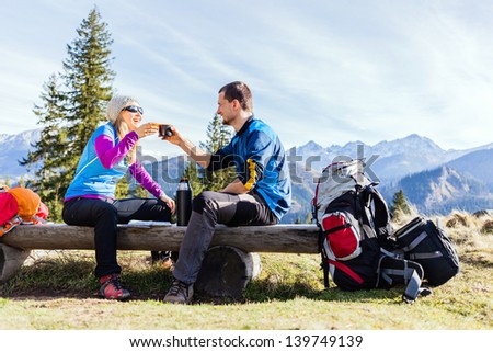 Man and woman, hikers camping in mountains. Young couple drinking and planning trip.