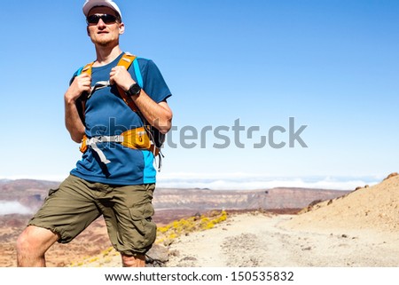 Trail runner, man walking or running in mountains with backpack. Running, sports, fitness and healthy lifestyle outdoors in summer nature