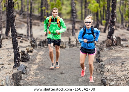 Man and woman trail running on volcanic trail in mountains. Young couple runners in forest  on beautiful island La Palma, Canary Islands.