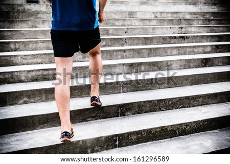 Man runner running on stairs in city. Young male athlete jogging, training and doing workout outdoors in city. Fitness and exercising outdoors urban environment.