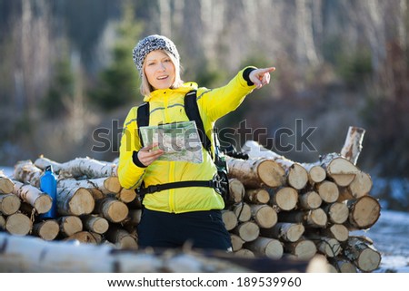 Woman hiking in forest reading map. Recreation and healthy lifestyle outdoors in nature. Beauty blond looking at camera on sunset.
