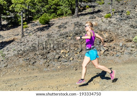 Young woman trail running in mountains on sunny summer day. Beauty female runner jogging and exercising outdoors in nature, rocky trail footpath on La Palma, Canary Islands
