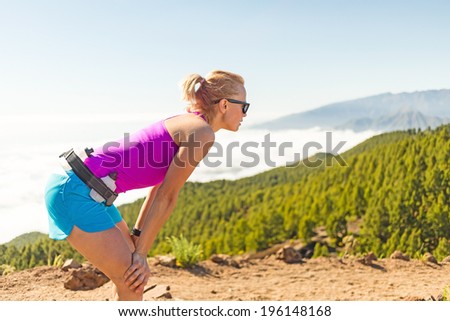 Young woman cross country running in mountains on sunny summer day. Beauty female runner jogging and exercising outdoors in nature, rocky trail footpath on La Palma, Canary Islands
