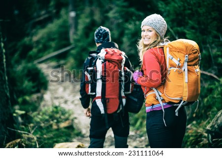 Man and woman hikers trekking in mountains. Young couple walking with backpacks in forest, Tatras in Poland. Old vintage photo style.