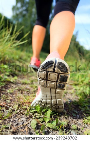 Woman walking or running exercise motivation and inspiration activity, legs on footpath green grass in forest, achievement fitness adventure and exercising in spring or summer nature healthy lifestyle