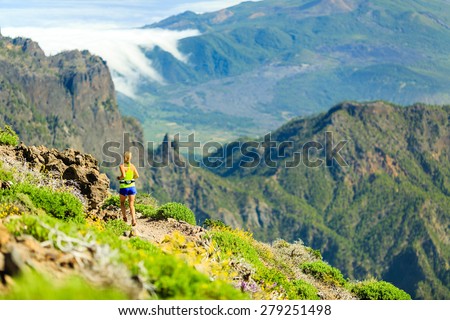 Young woman running or power walking in mountains on sunny summer day. Beautiful natural landscape and female runner jogging exercising outdoors in nature, rocky trail footpath on Canary Islands